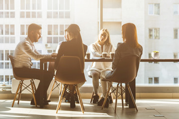 Wall Mural - A team of young businessmen working and communicating together in an office. Corporate businessteam and manager in a meeting. desktop against the background of the pan window, free space for text