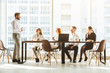 © xartproduction - A team of young businessmen working and communicating together in an office. Corporate businessteam and manager in a meeting. desktop against the background of the pan window, free space for text