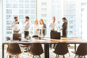 Wall Mural - A team of young businessmen working and communicating together in an office. Corporate businessteam and manager in a meeting. desktop against the background of the pan window, free space for text