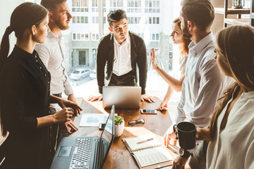 Wall Mural - A team of young businessmen working and communicating together in an office. Corporate businessteam and manager in a meeting.