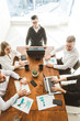 © xartproduction - A team of young businessmen working and communicating together in an office. Corporate businessteam and manager in a meeting.