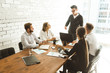 © xartproduction - A team of young businessmen working and communicating together in an office. Corporate businessteam and manager in a meeting.