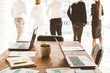 © xartproduction - work area on the table in the foreground. A team of young businessmen working and communicating together in an office. Corporate businessteam and manager in a meeting.