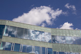 Fototapeta Na sufit - Reflections of the sky and clouds on a modern facade of a building on a summer day