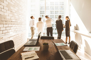 Wall Mural - work area on the table in the foreground. A team of young businessmen working and communicating together in an office. Corporate businessteam and manager in a meeting.