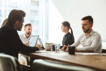 A team of young businessmen working and communicating together in an office. Corporate businessteam and manager in a meeting.