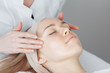 © Rithor - Unknown masseuse beautician doing a face massage to her client a beautiful young woman. Skin care concept