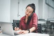 © Looker_Studio - beautiful asian woman using smartphone and computer laptop in coffee shop and she's smiling face and writing note.