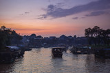 Fototapeta Boho - Fisherman boat driving through floating native floating village on pylons Kampong Phluk in Cambodia Asia