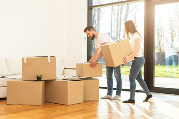 Wall Mural - young couple moves to a new home. the family carries boxes of things after buying a home.