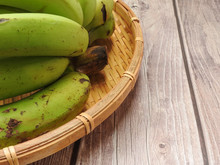High Angle View Of A Bunch Of Green Bananas On Bamboo Plate On Wooden