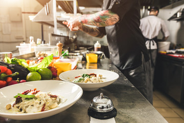 Sticker - Professional chef cooking in the kitchen restaurant at the hotel, preparing dinner. A cook in an apron makes a salad of vegetables and pizza.