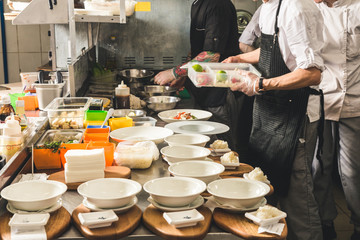 Wall Mural - Professional chef cooking in the kitchen restaurant at the hotel, preparing dinner. A cook in an apron makes a salad of vegetables and pizza.