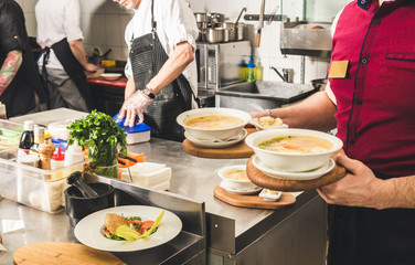 Professional chef cooking in the kitchen restaurant at the hotel, preparing dinner. A cook in an apron makes a salad of vegetables and pizza.