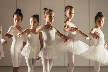 Young caucasian ballerinas stretching before performance isolated in classical dance school, young professional dancers