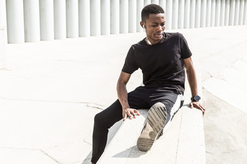 Wall Mural - Athletic young afroamerican runner doing warm up on the promenade. Black Male running on outdoors. Healthy lifestyle concept.