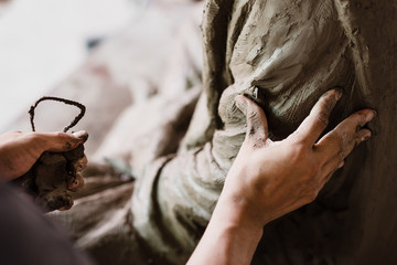 Selective focus sculptor hand molding clay.Professional artist worker creating a statue sculpture with wet clay.