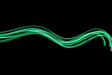 Long Exposure Photograph Of Neon Green Colour In An Abstract Swirl, Parallel Lines Pattern Against A Black Background. Light Painting Photography.