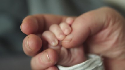 hand in hand. grandmother holds the hand of a newborn. little tinny newborn baby holding finger of t