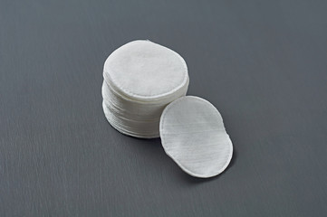 Heap of round cotton pads for hygiene lies on dark concrete table. Close-up