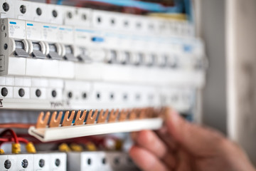 Wall Mural - Man, an electrical technician working in a switchboard with fuses. Installation and connection of electrical equipment. Close up.