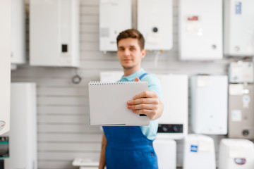 Wall Mural - Plumber at showcase with boilers, plumbering store