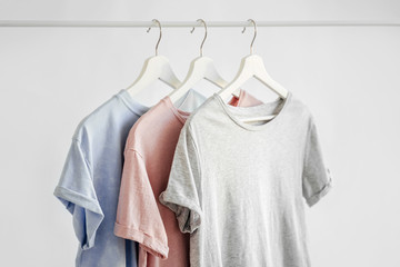Wall Mural - T-Shirts in pastel color on hanger on white background. Basic female clothes. Spring/summer outfit.