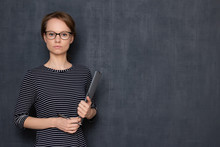 Portrait Of Serious Young Woman Holding Folder And Pen In Hands