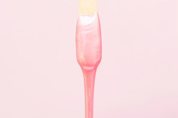 liquid wax for pink depilation drains from the stick. The concept of depilation, waxing, smooth skin without hair.