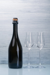 champagne bottle and two empty glasses on a gray background