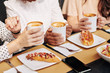 © DragonImages - Female friends or colleagues drinking coffee and eating hotdogs at lunch in cafe