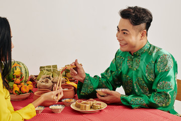 Poster - Young Asian couple enjoying tasty traditional food at Lunar New Year celebration