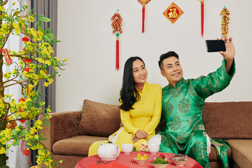 Poster - Happy young Vietnamese couple taking selfie when celebrating Lunar New Year at home