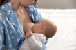 © New Africa - Young woman breast feeding her little baby on bed, closeup