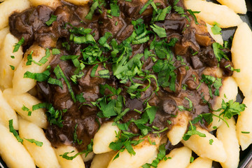 Freshly cooked, Polish traditional potato dumplings serving with mushroom sauce and fresh parsley