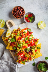 Poster - Nachos chips with cheese sauce, guacomole, salsa and vegetables on the board, top view. Party food concept.