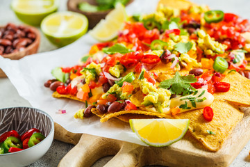 Poster - Nachos chips with cheese sauce, guacomole, salsa and vegetables on the board. Party food concept.