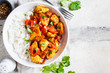 © vaaseenaa - Jalfrezi chicken with rice in white bowl, top view, copy space. Traditional indian cuisine concept.