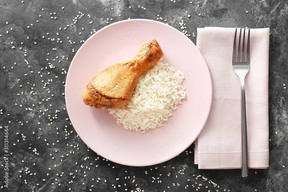 Plate with tasty rice and chicken on dark background