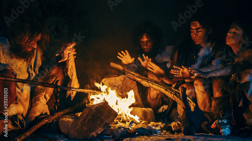 Fotografía Neanderthal or Homo Sapiens Family Cooking Animal Meat over Bonfire and then Eating it