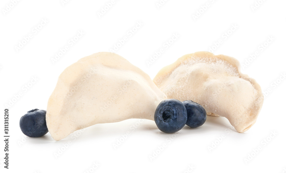 Raw dumplings with blueberries on white background