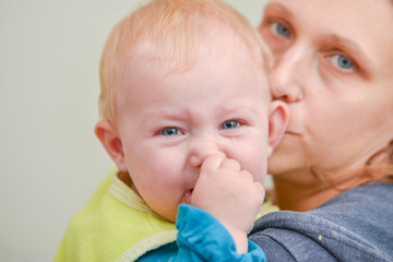 A small child sits in her mother’s arms and cries with tears in her eyes.