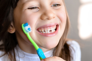 Wall Mural - Beautiful smiling preschool girl with her first adult incisor tooth. Cute child showing her baby milk tooth fell out  and her growing permanent tooth in open mouth. Dental hygiene concept