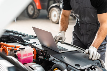 Wall Mural - cropped view of mechanic using laptop near car engine compartment