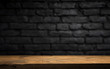 Wood table in front of rustic brick wall blur background with empty copy space on the table for product display mockup. Retro design montage presentation.