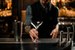 © fesenko - Male bartender holding an emty cocktail glass near steel shaker