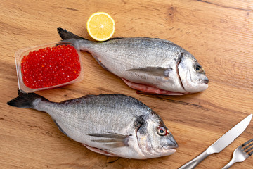 Fresh raw dorado fish with spices. Ingredients for cooking or grill on cutting board. Top view, copy space