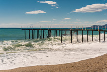 Beach, Sea And Pier In The City Of Mahmutlar. Against The Blue Sky With White Clouds