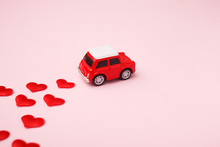 Red Retro Toy Red Car With Red Bow For Valentine's Day On Pink Background With Heart Confetti