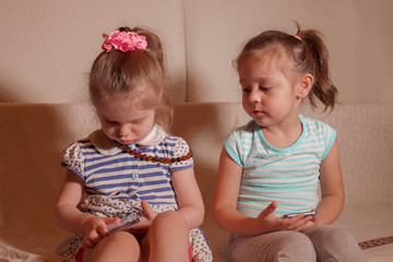 two small girls playing by phone at home